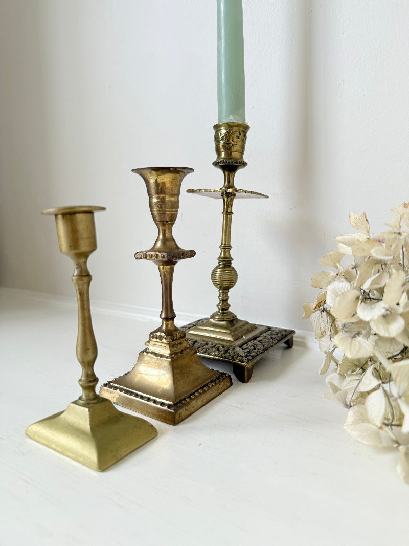 vintage brass trio of candlesticks in mixed designs photographed on white surface