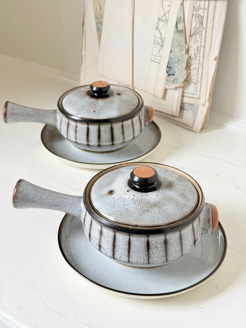 Denby Studio pair of lidded soup bowls with stands in grey and rust photographed on a white surface