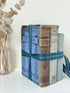 Vintage blue fabric bound decorative book bundle tied with blue and green tartan ribbon, photographed on a white surface