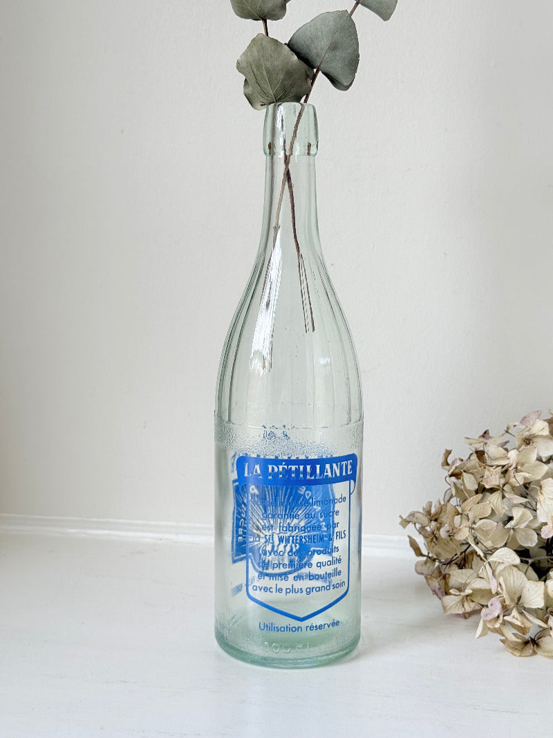 vintage french lemonade bottle la pétillante blue label on white surface with hydrangea flowers
