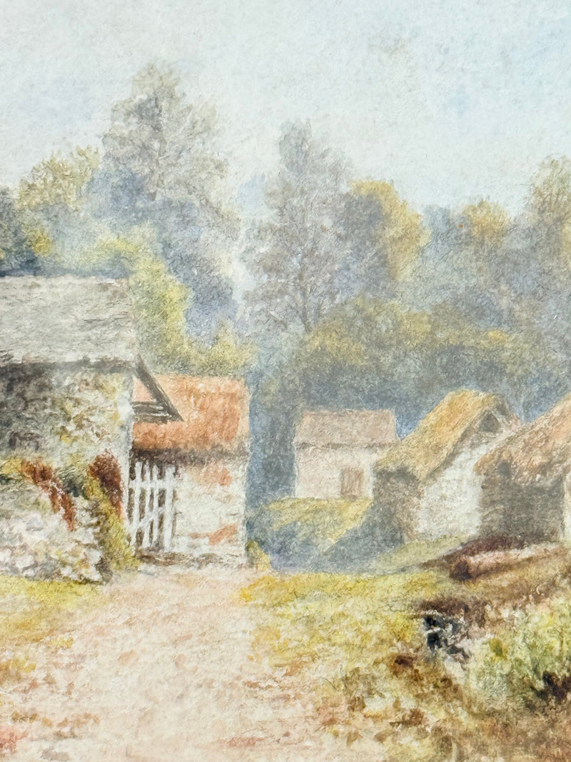 Framed vintage watercolour of countryside farm buildings with red roofs in gold frame photographed on a white surface