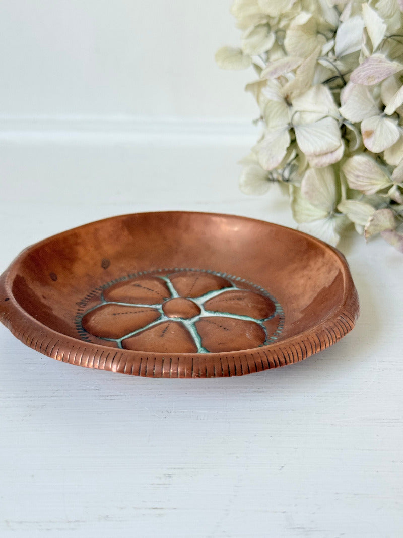 small vintage copper dish with cut-out floral centre photographed on white surface