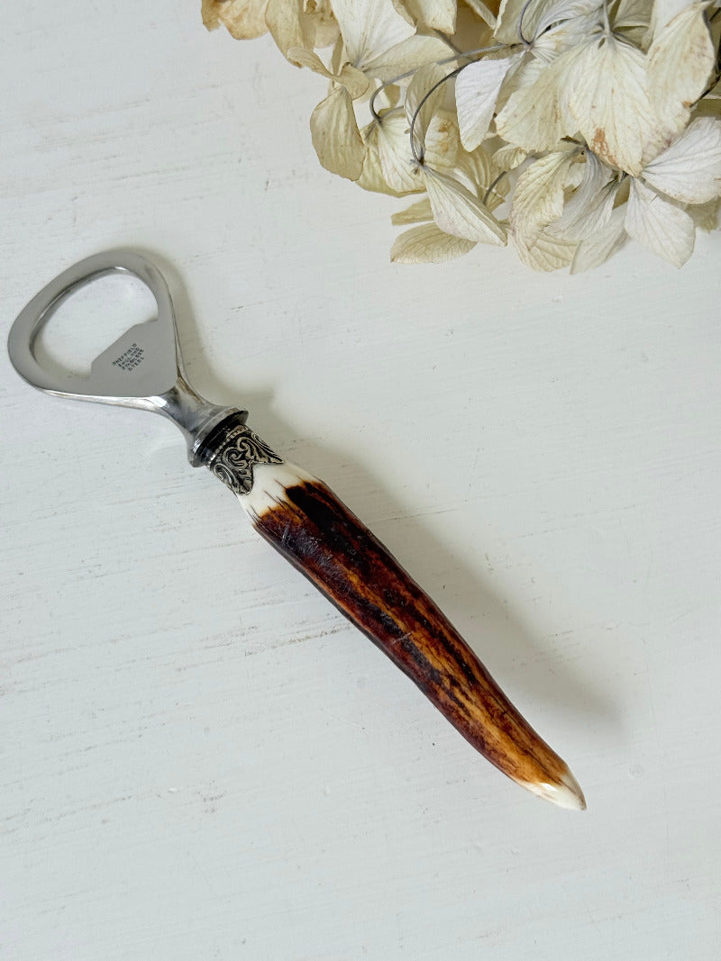 vintage antler handle bottle opener with stainless steel top photographed on white surface