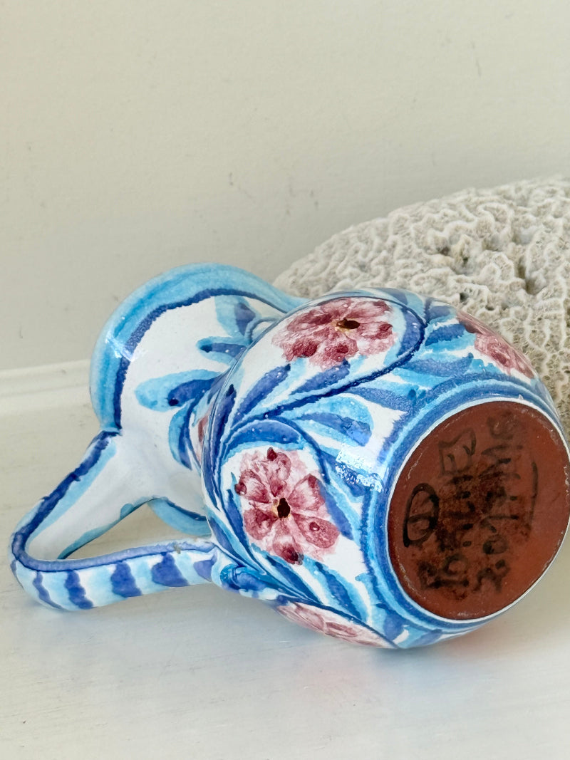Portuguese studio pottery jug with blue and pink hand painted floral design, photographed on a white surface