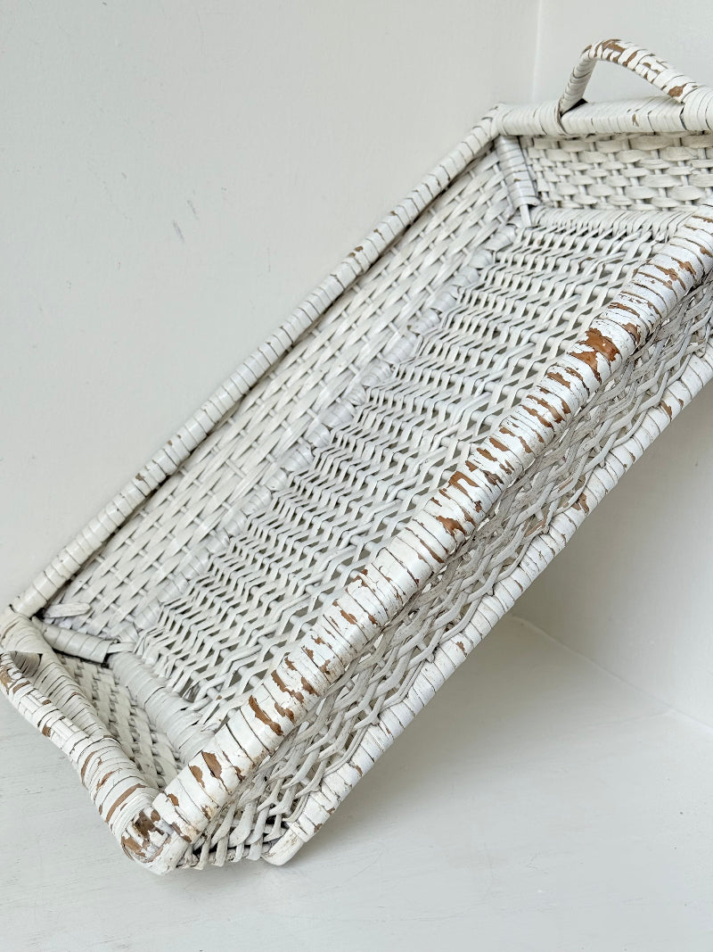 Vintage white painted wicker tray with woven handles photographed on a white surface