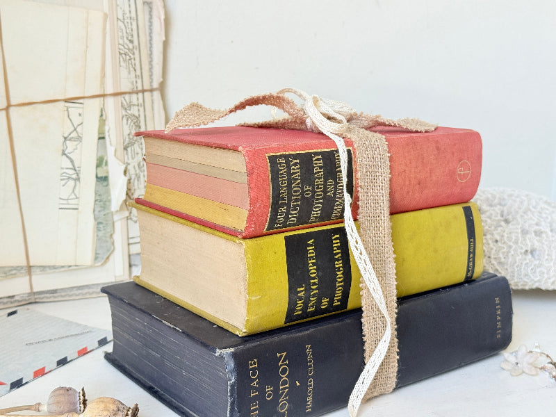 Vintage decorative book bundle in blue yellow and red with aged hardback covers tied with natural ribbon for bookshelf styling
