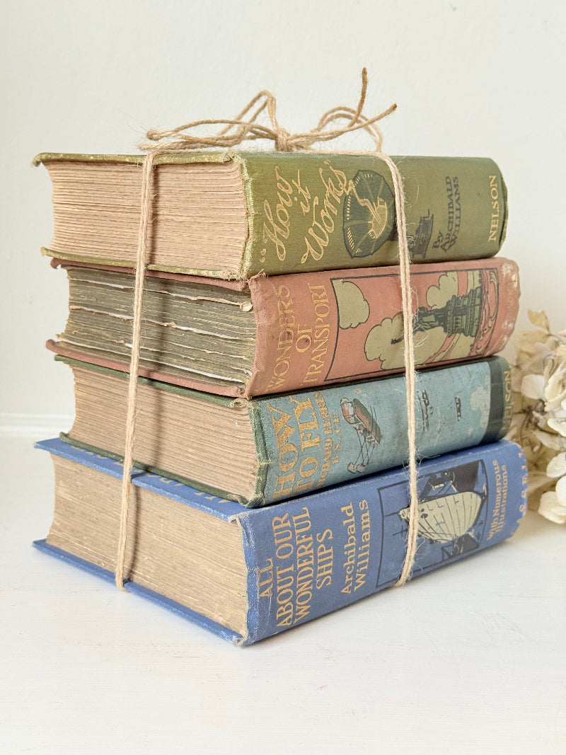 Vintage decorative book bundle in green, blue, and coral with printed lettering, tied with twine, photographed on a white surface