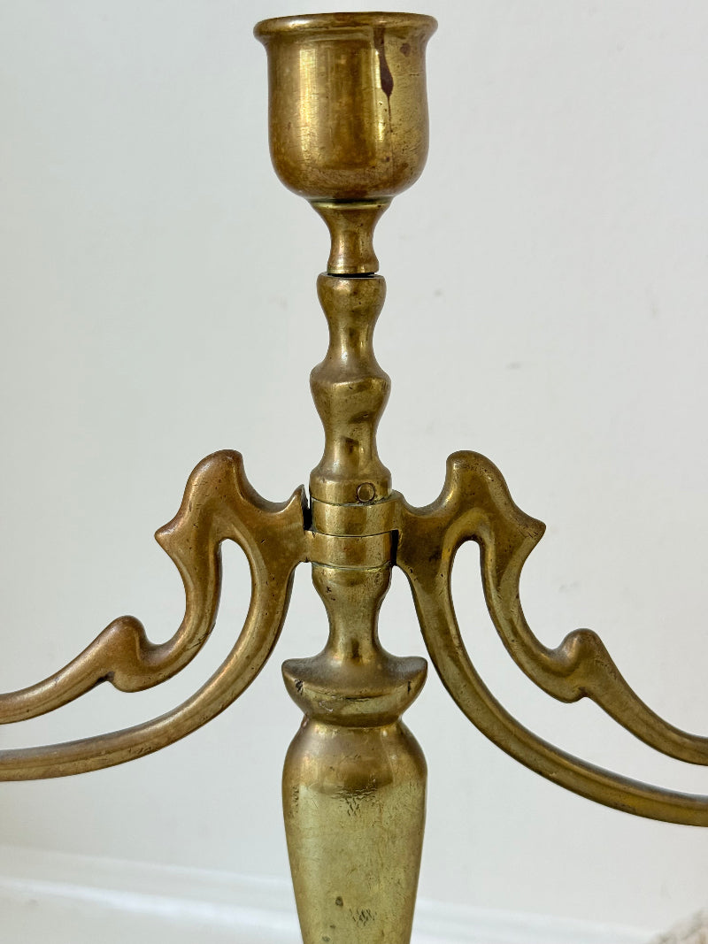 Vintage brass three-arm candelabra with curved arms and soft patina, photographed on a white surface