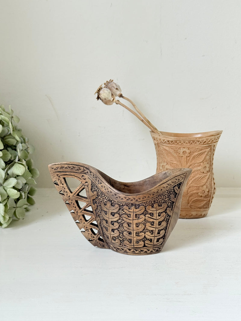 Pair of hand carved wooden jug and vase in contrasting light and dark tones, styled with dried poppy heads on a white surface.