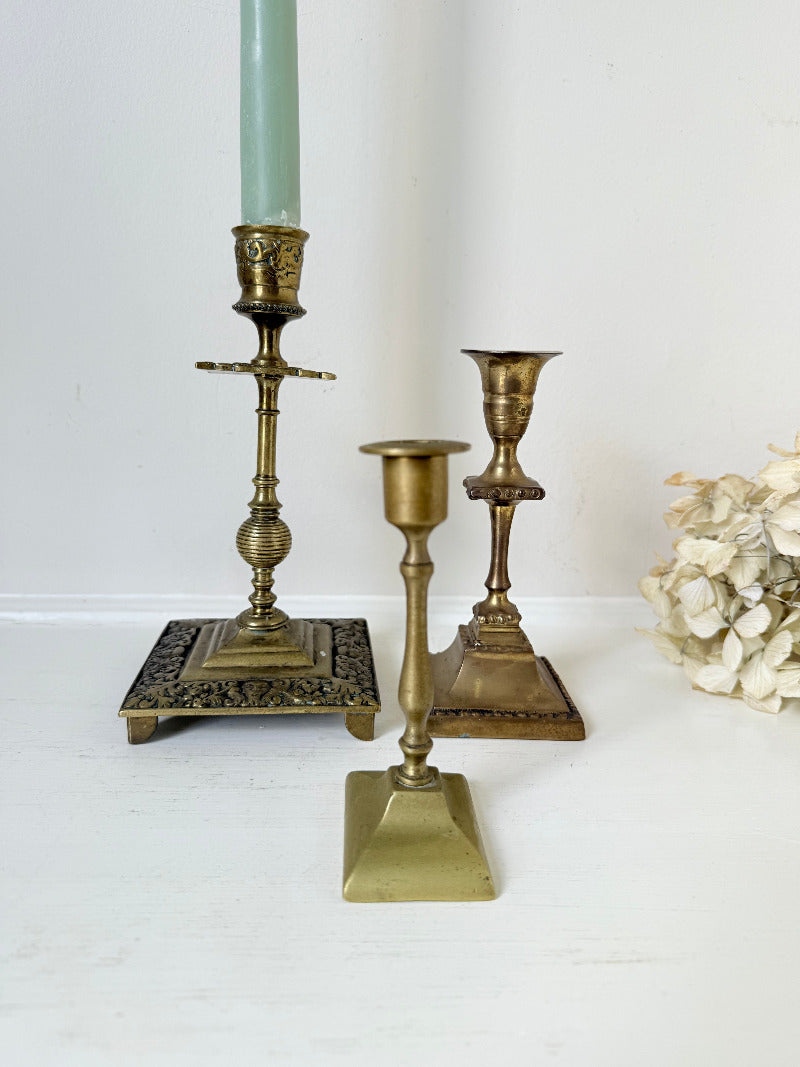 vintage brass trio of candlesticks in mixed designs photographed on white surface