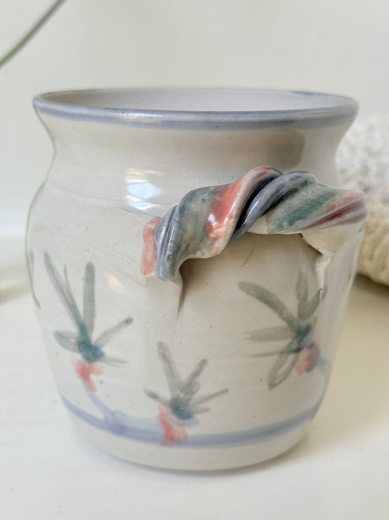 Vintage studio pottery utensil pot with hand painted floral decoration and applied handle detail, photographed on a white surface