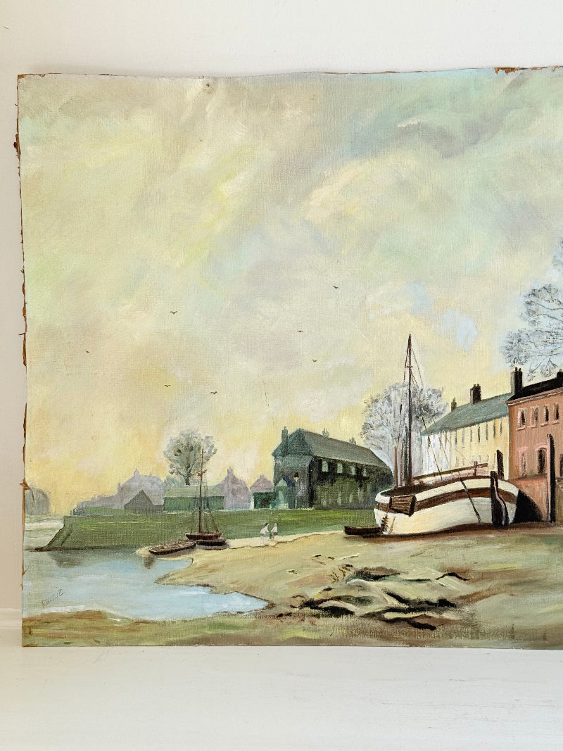 Vintage oil painting on board of a rural village scene with houses, trees, and water, photographed on a white surface