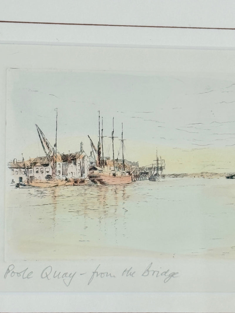 Framed vintage print of Poole Quay harbour scene in muted tones, under glass with gilt and wood-effect frame, on white surface.