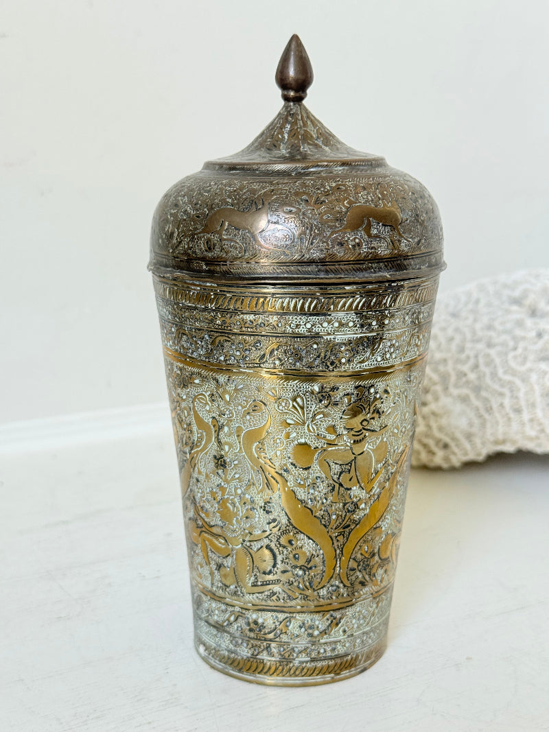 Indian Benares brass jar with lid and engraved animals and floral design, photographed on a white surface