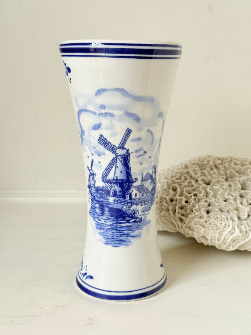 Blue and white Delft hand painted ceramic vase with windmill and floral decoration, photographed on white surface.