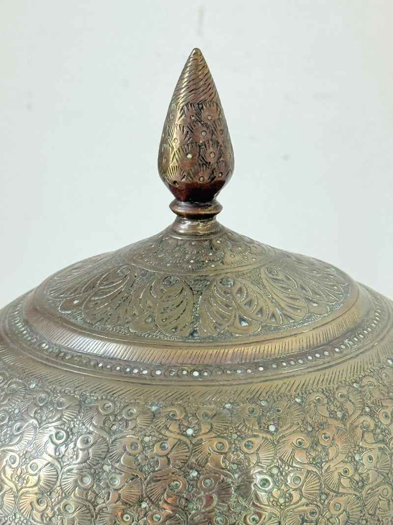 Indian Benares brass lidded jar with floral engraving and finial, photographed on a white surface