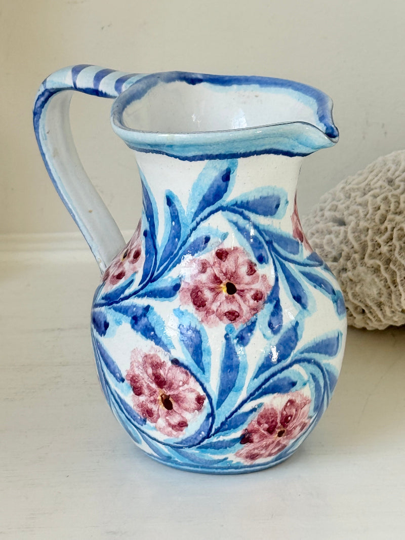 Portuguese studio pottery jug with blue and pink hand painted floral design, photographed on a white surface