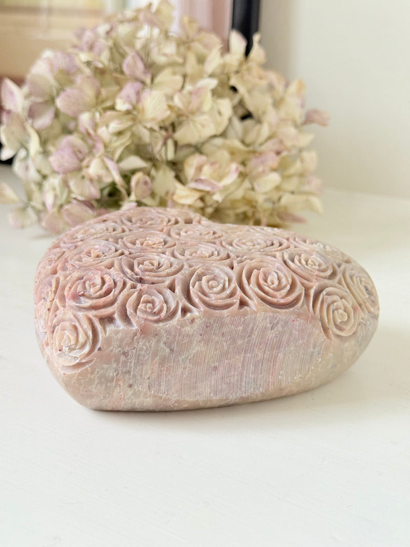 vintage pink stone heart with engraved roses and flat base on white surface