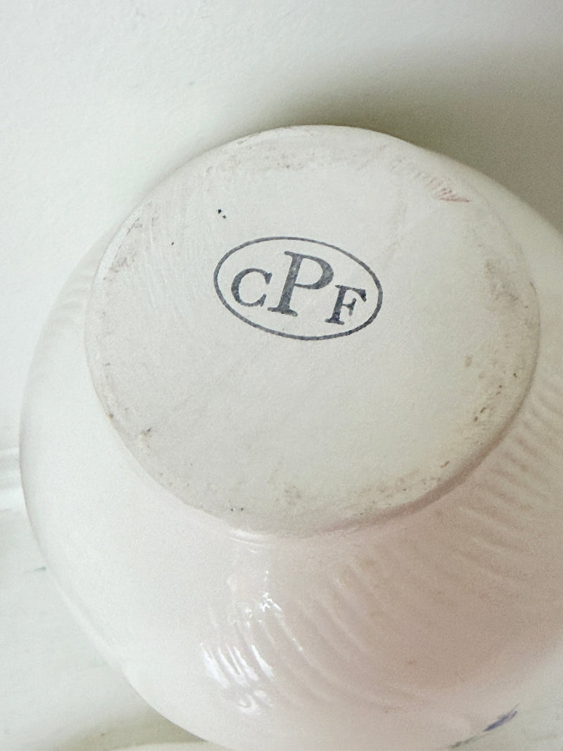 Close-up of the bottom of a white ceramic bowl or vase, showing a circular base printed with the letters &