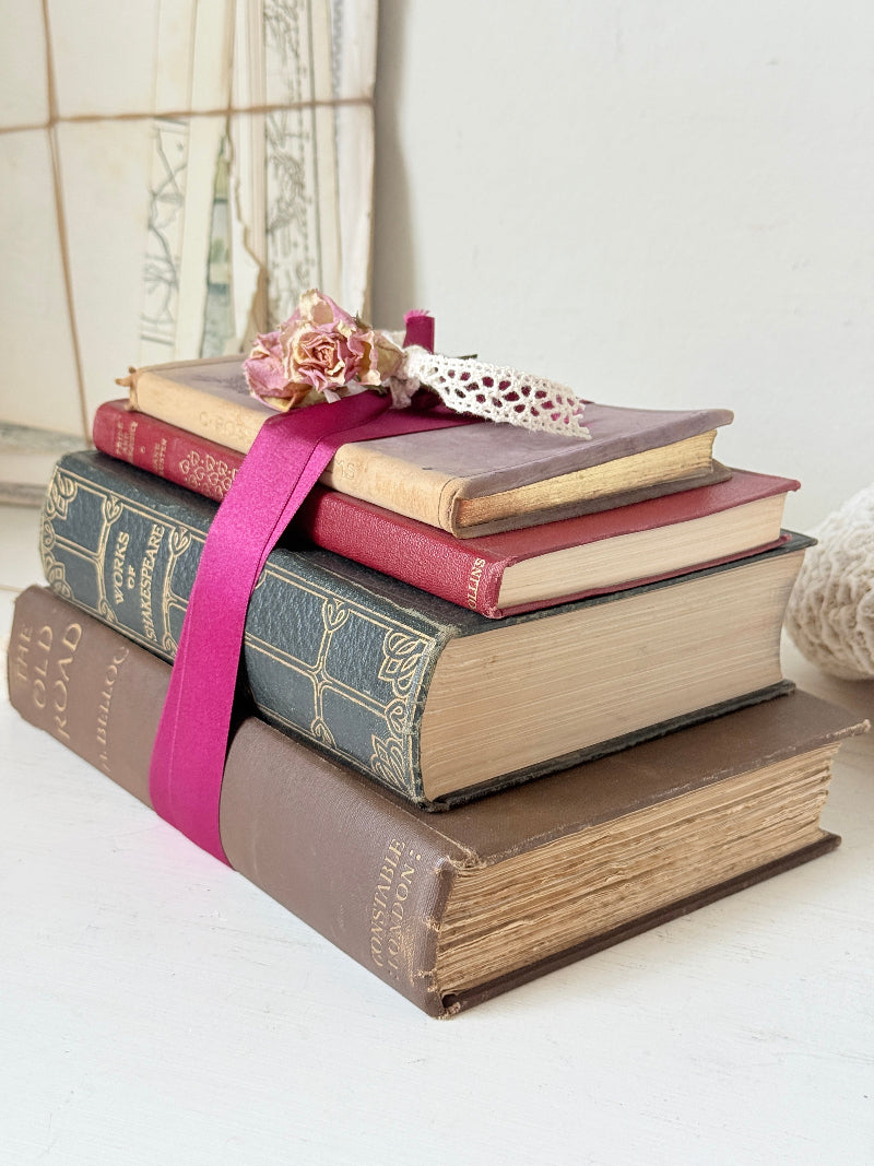 Vintage decorative book bundle with pink ribbon, dried flower detail and aged hardback covers for shelf and table styling