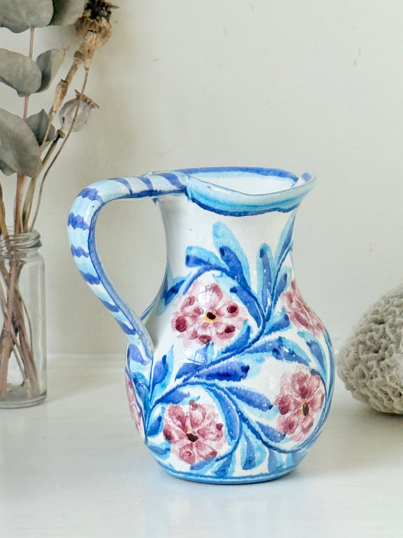 Portuguese studio pottery jug with blue and pink hand painted floral design, photographed on a white surface
