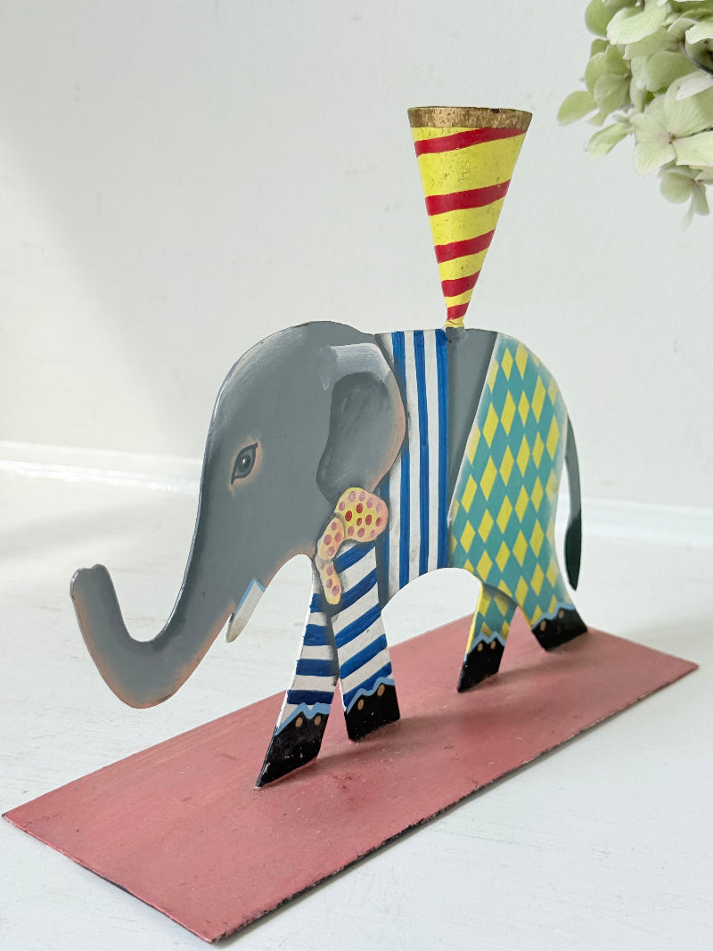 Hand painted metal elephant candlestick in circus-style decoration with colourful patterns, photographed on a white surface