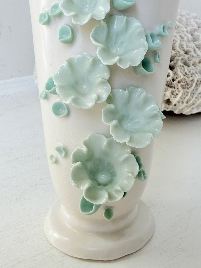 White Chessell Pottery studio vase with rippled rim and raised aqua floral decoration photographed on a white surface
