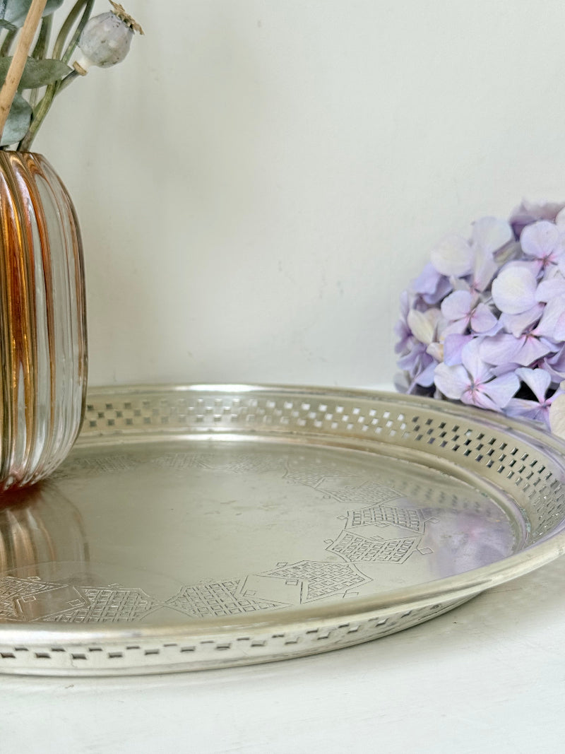 Vintage round silver plate tray with brass rim, pierced edge and etched central motif, photographed on white surface