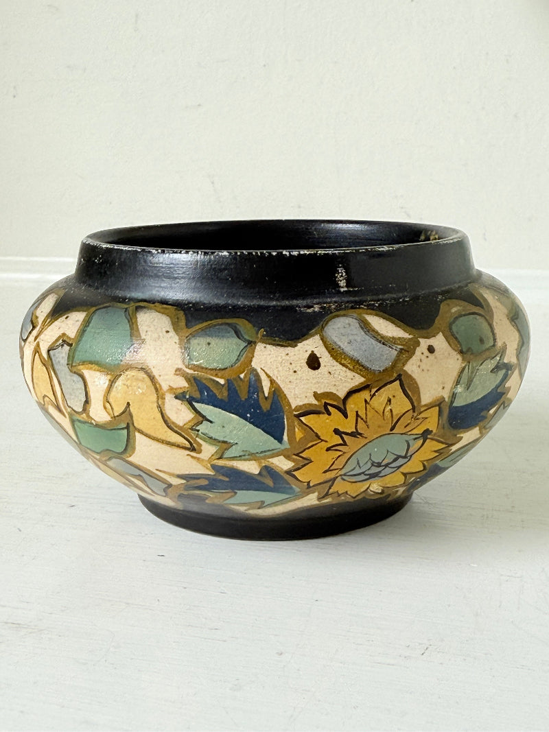 Brentleigh Ware Art Deco pottery jar with hand painted floral decoration on a black ground, photographed on a white surface