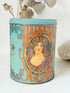 Vintage turquoise and gold metal sweet tin with Art Nouveau woman portrait photographed on a white surface.