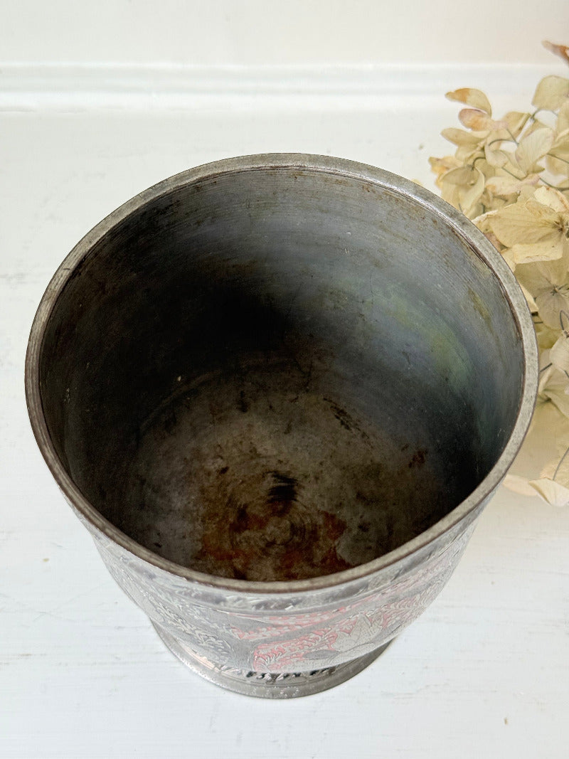 vintage indian metal lassi cup with red and white enamel motifs, styled with dried hydrangeas on a white surface