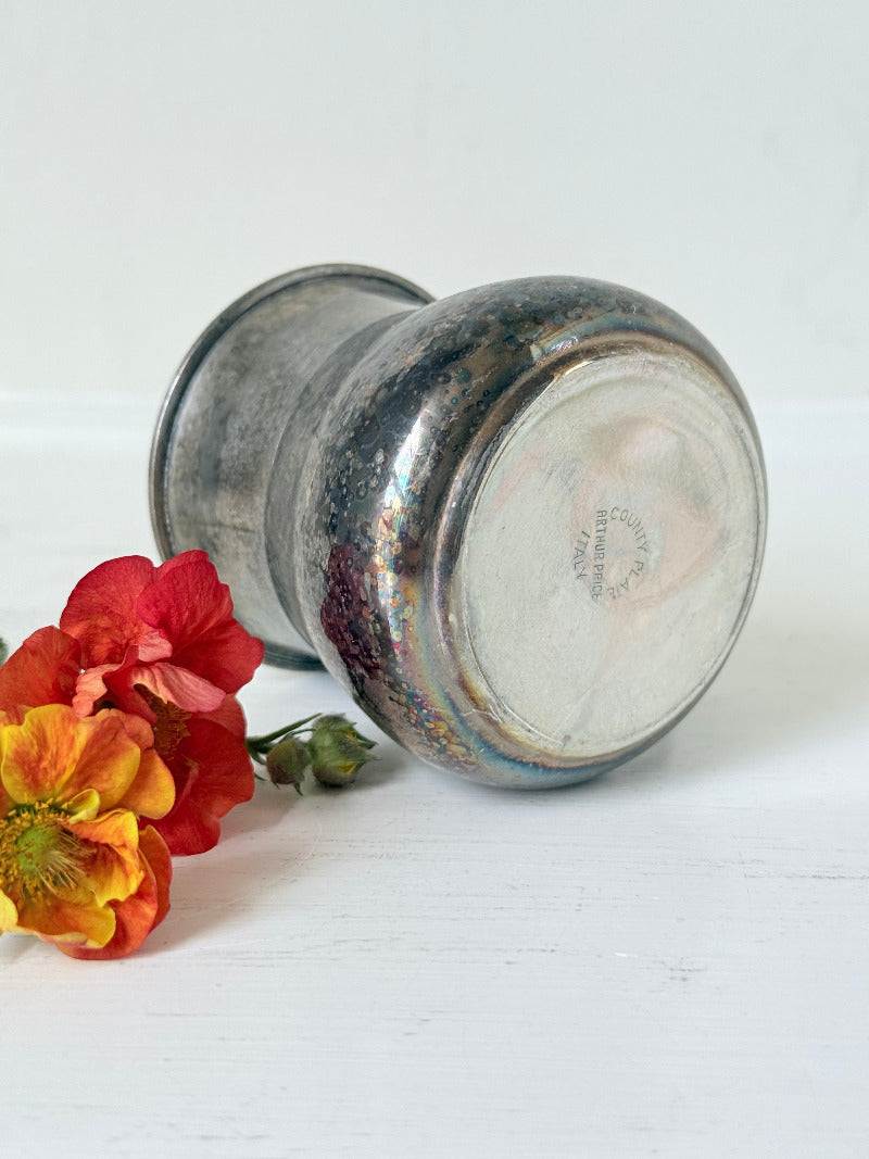 vintage silver plate beaker by arthur price with ornate handle and patina, photographed with red flowers on a white surface