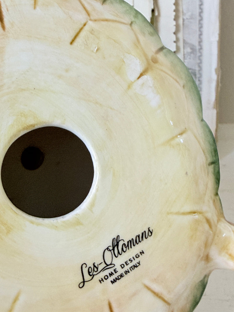 Close-up of a ceramic Les Ottaviani home decor piece, showing a cream-colored interior with a circular opening and the brand name printed in black script.
