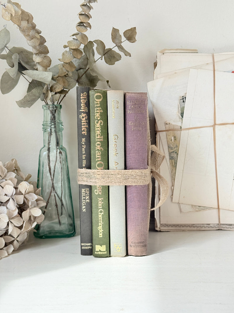 Bundle of vintage books with a heather purple cloth cover over green and cream spines tied with natural twine