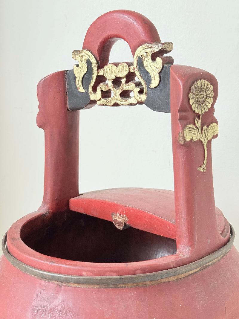 Vintage red painted wooden basket with upright handle and gold painted detail photographed on a white surface