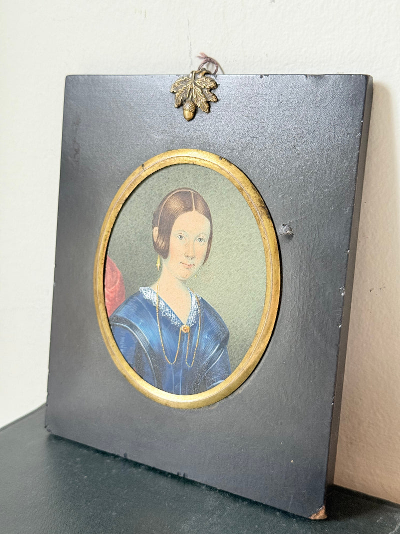 19th century watercolour miniature portrait of woman in blue dress, oval ebonised frame, styled on white background