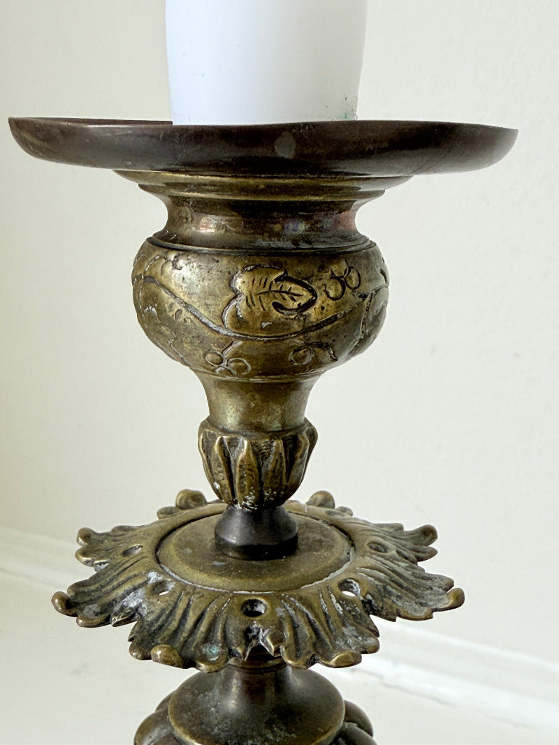 pair of antique brass candlesticks with turned detailing on white surface
