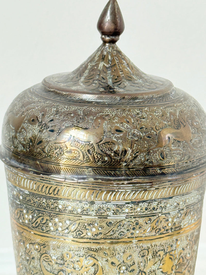 Indian Benares brass jar with lid and engraved animals and floral design, photographed on a white surface