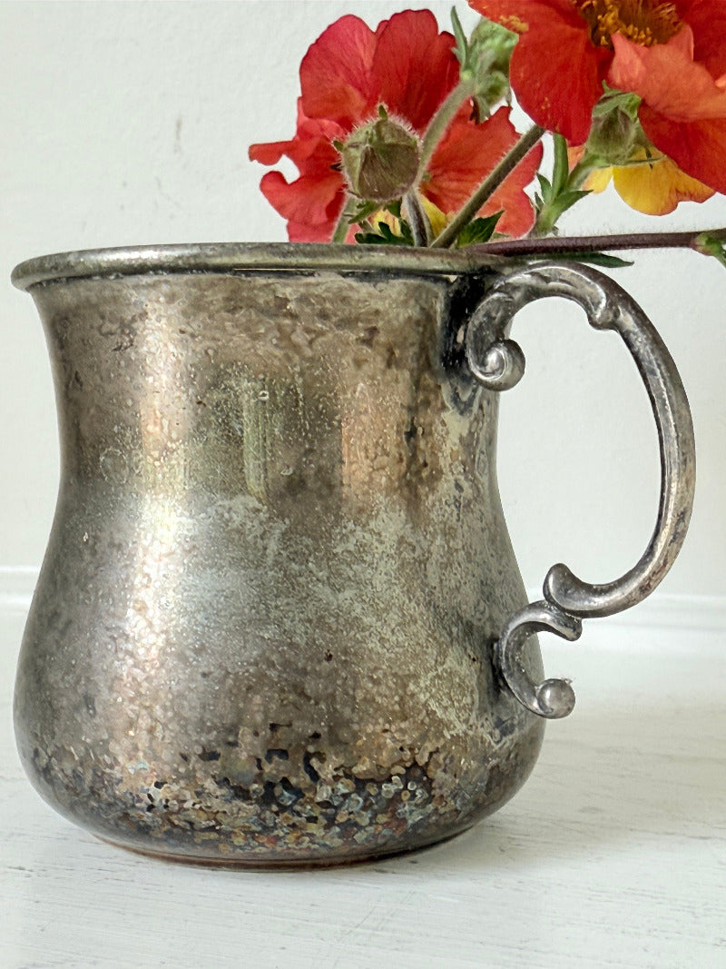 vintage silver plate beaker by arthur price with ornate handle and patina, photographed with red flowers on a white surface