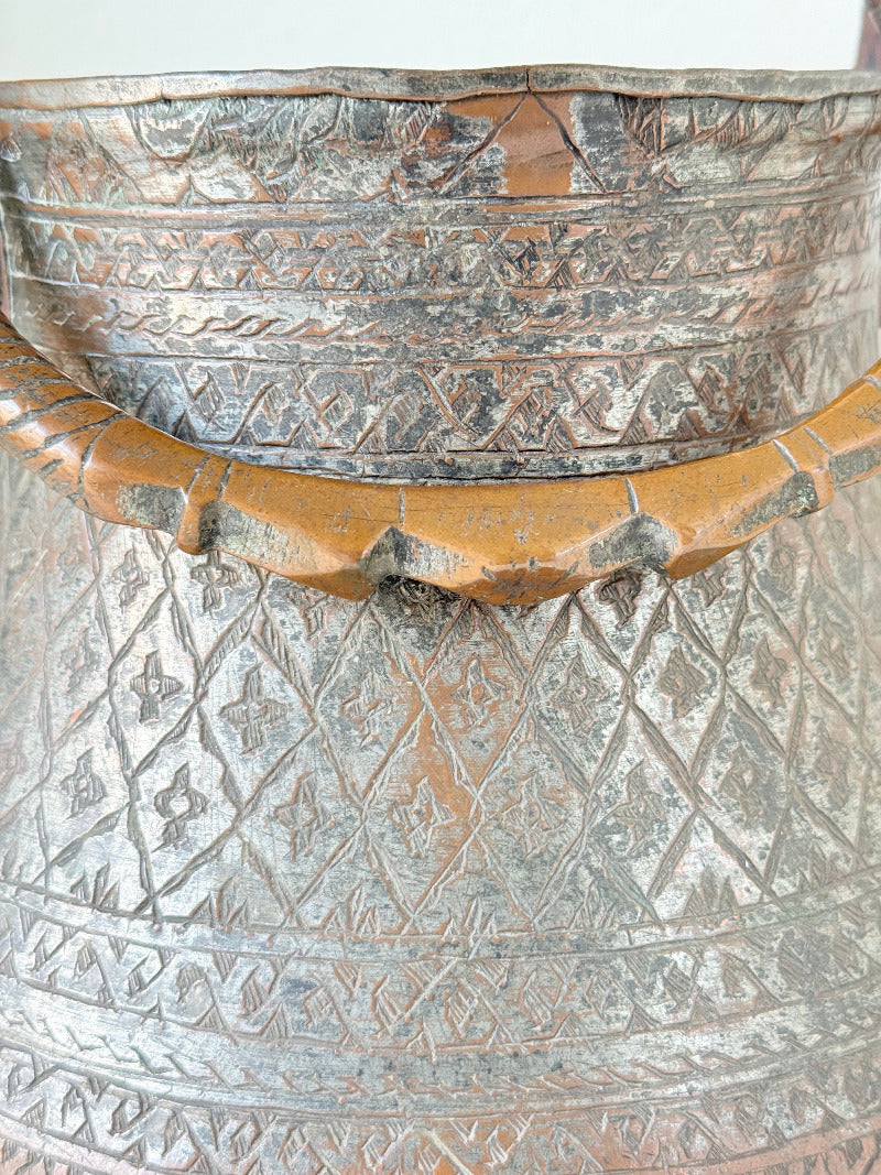 antique Middle Eastern water ewer with engraved diamond and foliate pattern and copper base, displayed on white surface