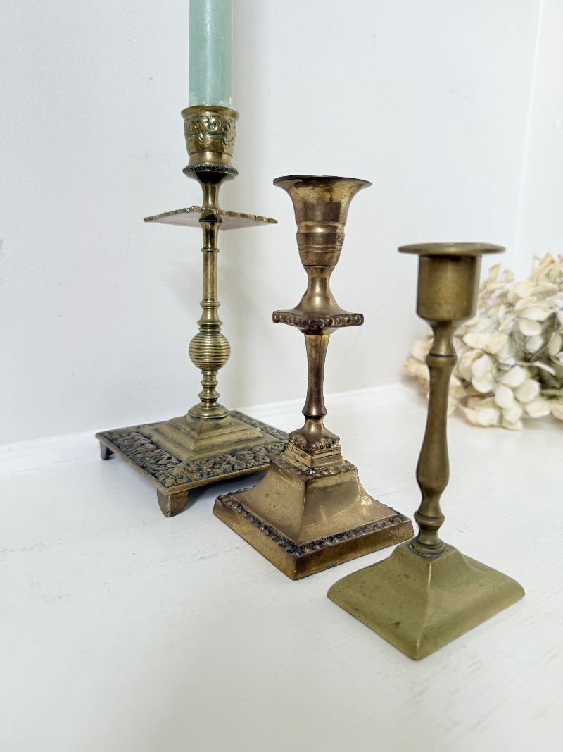vintage brass trio of candlesticks in mixed designs photographed on white surface
