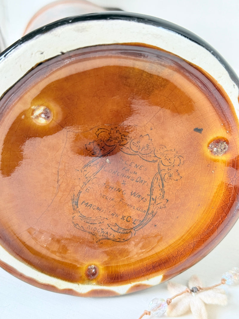 Antique Ridgways stoneware jug photographed on a white surface in amber treacle glaze with A Christmas Visitor black transfer scene and tall handle