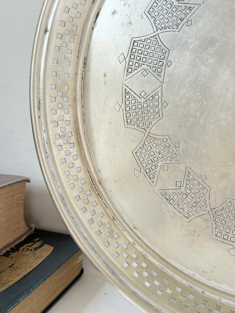 Vintage round silver plate tray with brass rim, pierced edge and etched central motif, photographed on white surface