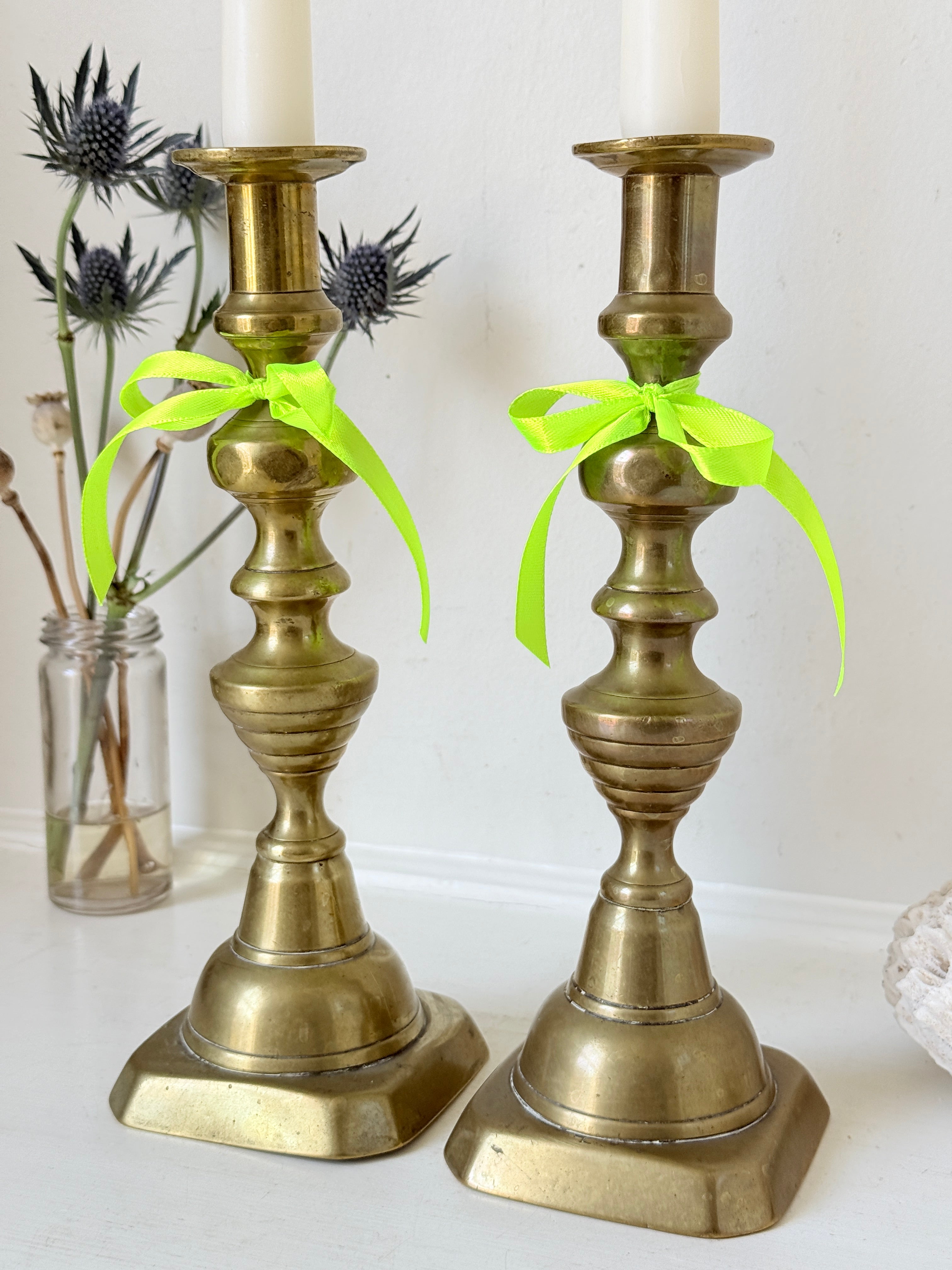 Pair of vintage brass candlesticks with turned stems and square bases, photographed on a white surface