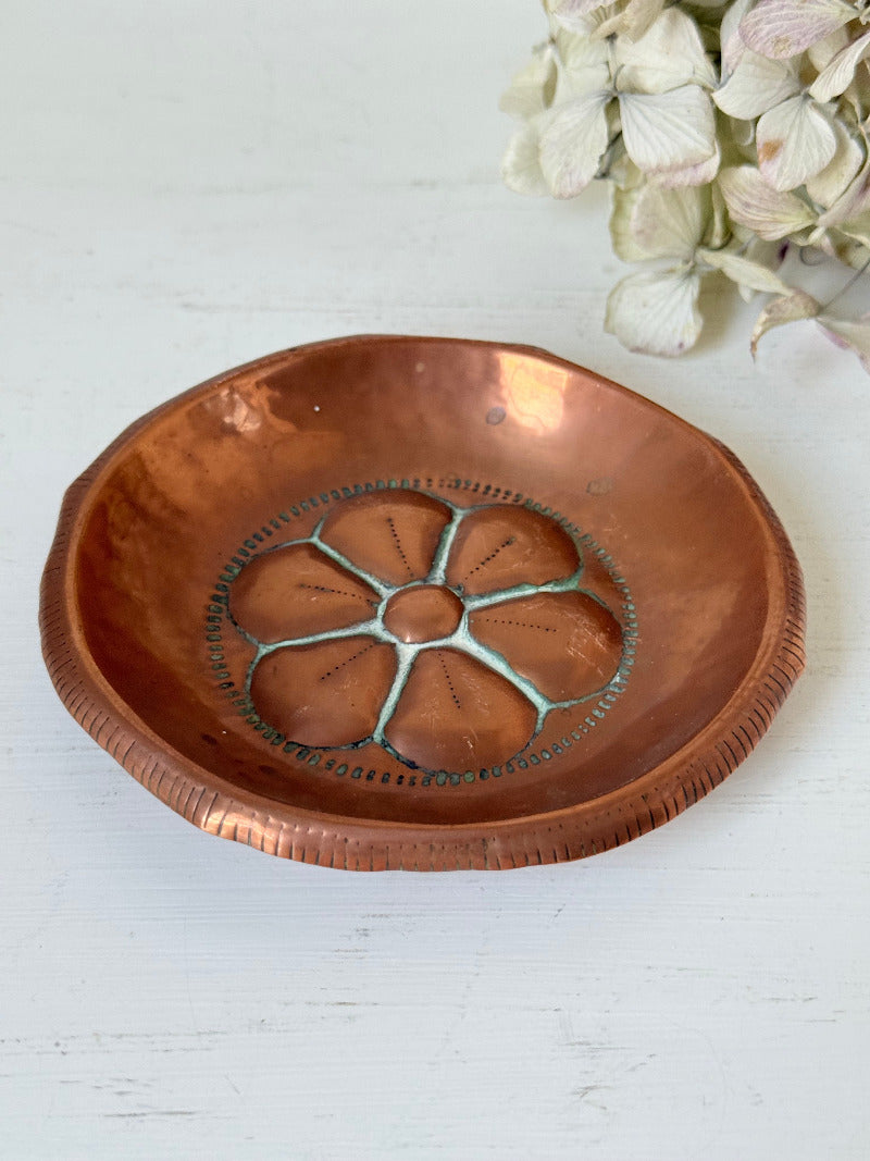 small vintage copper dish with cut-out floral centre photographed on white surface
