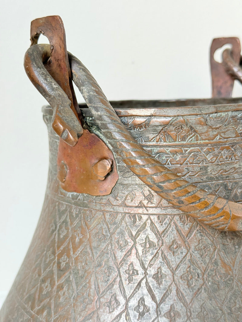 antique Middle Eastern water ewer with engraved diamond and foliate pattern and copper base, displayed on white surface