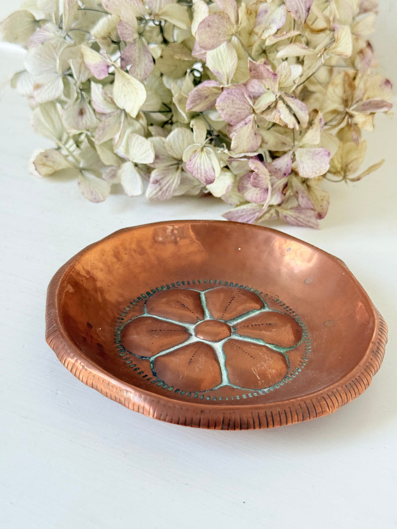 small vintage copper dish with cut-out floral centre photographed on white surface