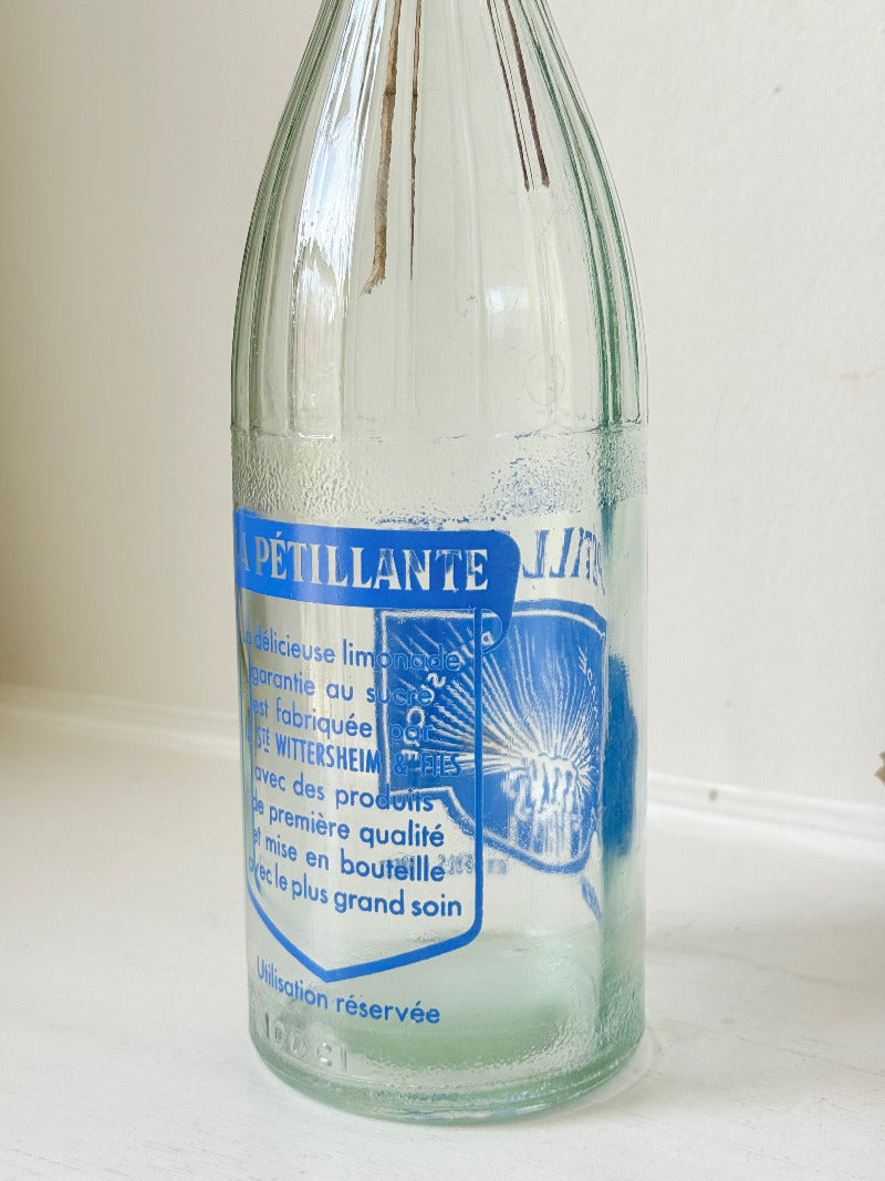 vintage french lemonade bottle la pétillante blue label on white surface with hydrangea flowers