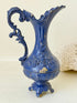 Blue vintage metal jug with ornate Rococo handle and relief decoration, shown on white background