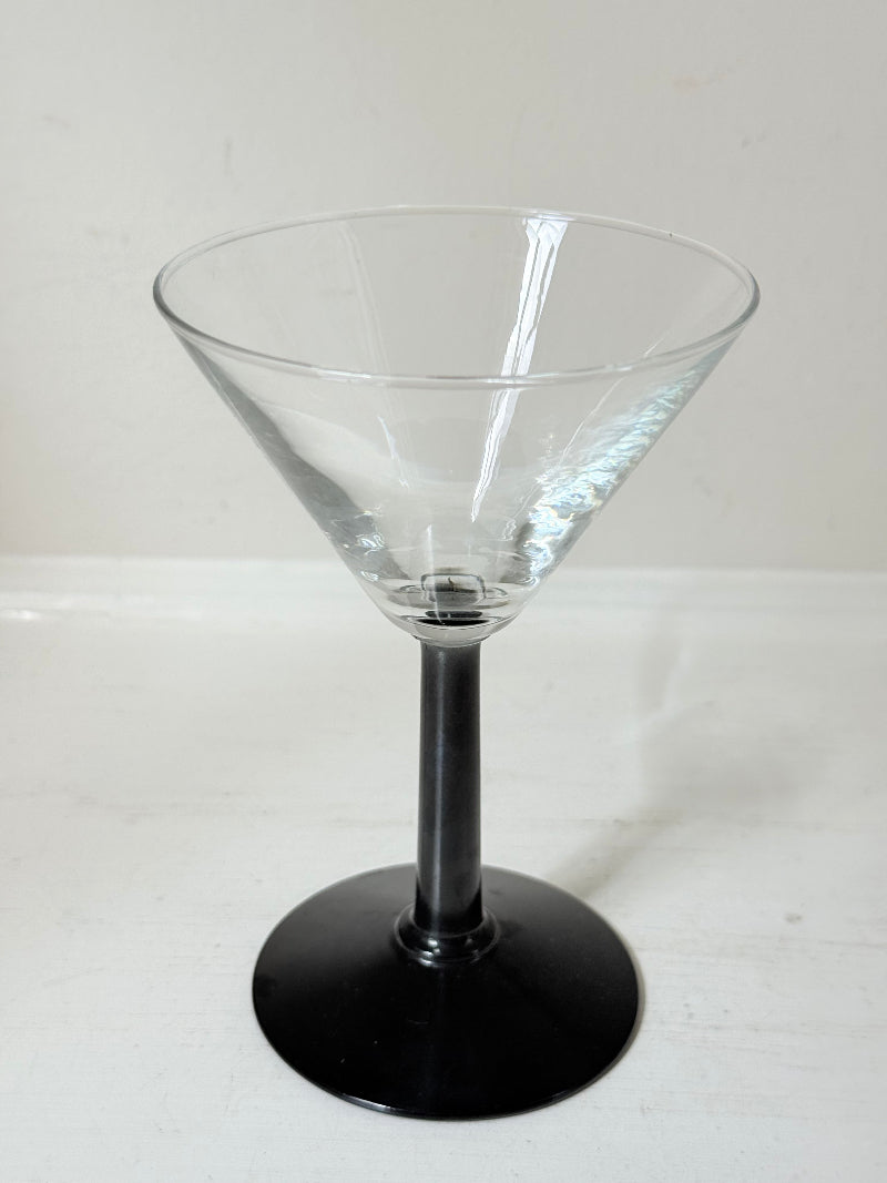 Set of six clear martini glasses with black stems, photographed on a white surface
